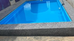 En rektangulär swimmingpool med blått kakel på insidan, omgiven av en grå stenkant.