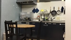 A compact kitchen with a dining table, chairs, and a stove. - Hostel Furoya (Osaka)