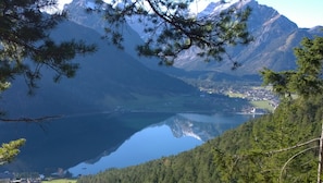 A mountainous landscape with a lake, dense forest, and a small settlement.