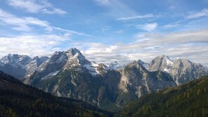 A mountainous landscape with snow-capped peaks and a valley with dense forest.