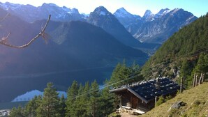 A mountain cabin with a view of a lake and snow-capped mountains.