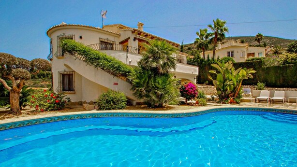 A Mediterranean-style villa with a swimming pool, surrounded by lush greenery and palm trees. - Nessa - well furnished villa with panoramic views in Benitachell (Benitachell)