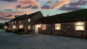 Une maison en briques avec de nombreuses fenêtres et une allée gravillonnée.