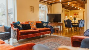 Un salon chaleureux avec un canapé rouge, des coussins à motifs et un plafond en bois.