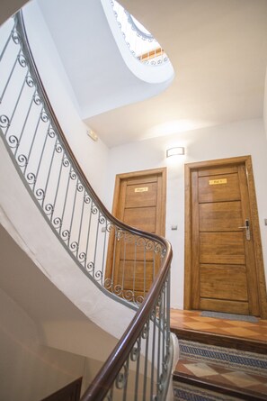 A staircase with a curved railing leading to a landing. There are two wooden doors labeled "Playa 1" and "Pal 1".