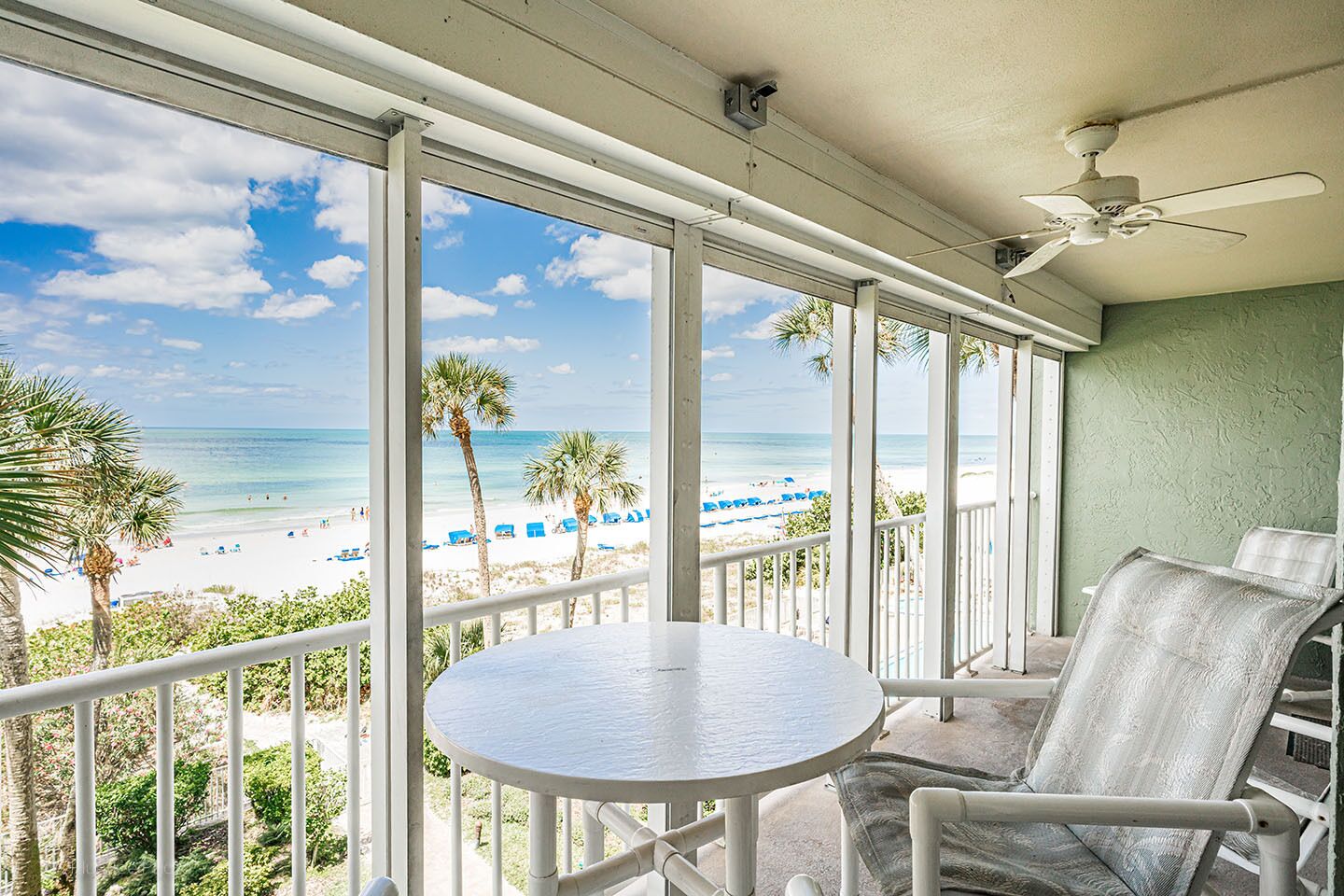 Un balcon avec vue sur la plage, une table et deux chaises.