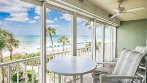 Ein Balkon mit Blick auf den Strand, einem Tisch und zwei Stühlen.