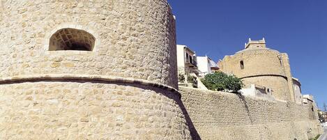 Une forteresse en pierre dotée d’une tour ronde et d’un bâtiment rectangulaire avec un balcon.
