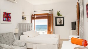 A bedroom with a bed, a chair, a TV, and a view of the sea. - MAR  - ESTUDIO CON VISTAS AL MAR (Villajoyosa)