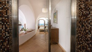 Un couloir donnant sur une chambre, avec un mur recouvert de carreaux et une armoire en bois.