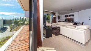 En moderne lejlighed med balkon, opholdsstue med sofa og sofabord, samt et køkkenområde.
