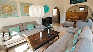 A modern living room with a sofa set, a coffee table with remote controls, and a TV. - Sola - pretty holiday property with garden and private pool in Benissa (Benissa)
