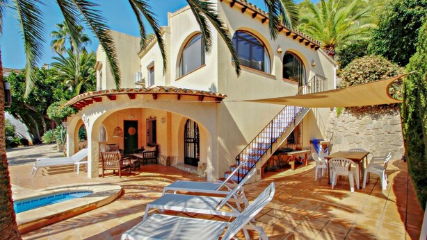 A Mediterranean-style villa with a swimming pool, outdoor seating, and a stone wall. - Sola - pretty holiday property with garden and private pool in Benissa (Benissa)