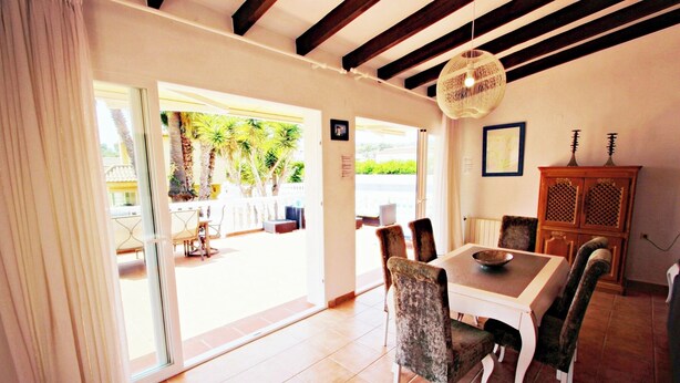 Un comedor con una mesa y sillas, una lámpara colgante y vistas al exterior.