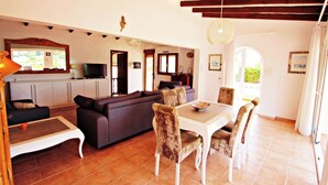 Una sala de estar con sofá, mesa de comedor, sillas y televisor.