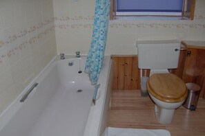 Un baño con bañera, inodoro y un armario de madera.