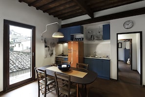 A kitchen with a dining table, chairs, and a view through a glass door.