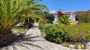 A stone pathway leading to a white building with a red-tiled roof, surrounded by lush greenery and palm trees. - El Tesorito Javea - Javea, Costa Blanca (Javea)