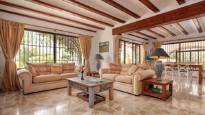 A spacious living room with two beige sofas, a coffee table, and a dining area with a white table and chairs. - El Tesorito Javea - Javea, Costa Blanca (Javea)