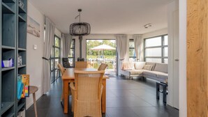 Una sala de estar moderna con comedor, ventanas amplias y vista a un lago.