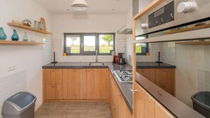 Una cocina moderna con armarios de madera, una campana extractora de acero inoxidable y una ventana con vistas al verdor.