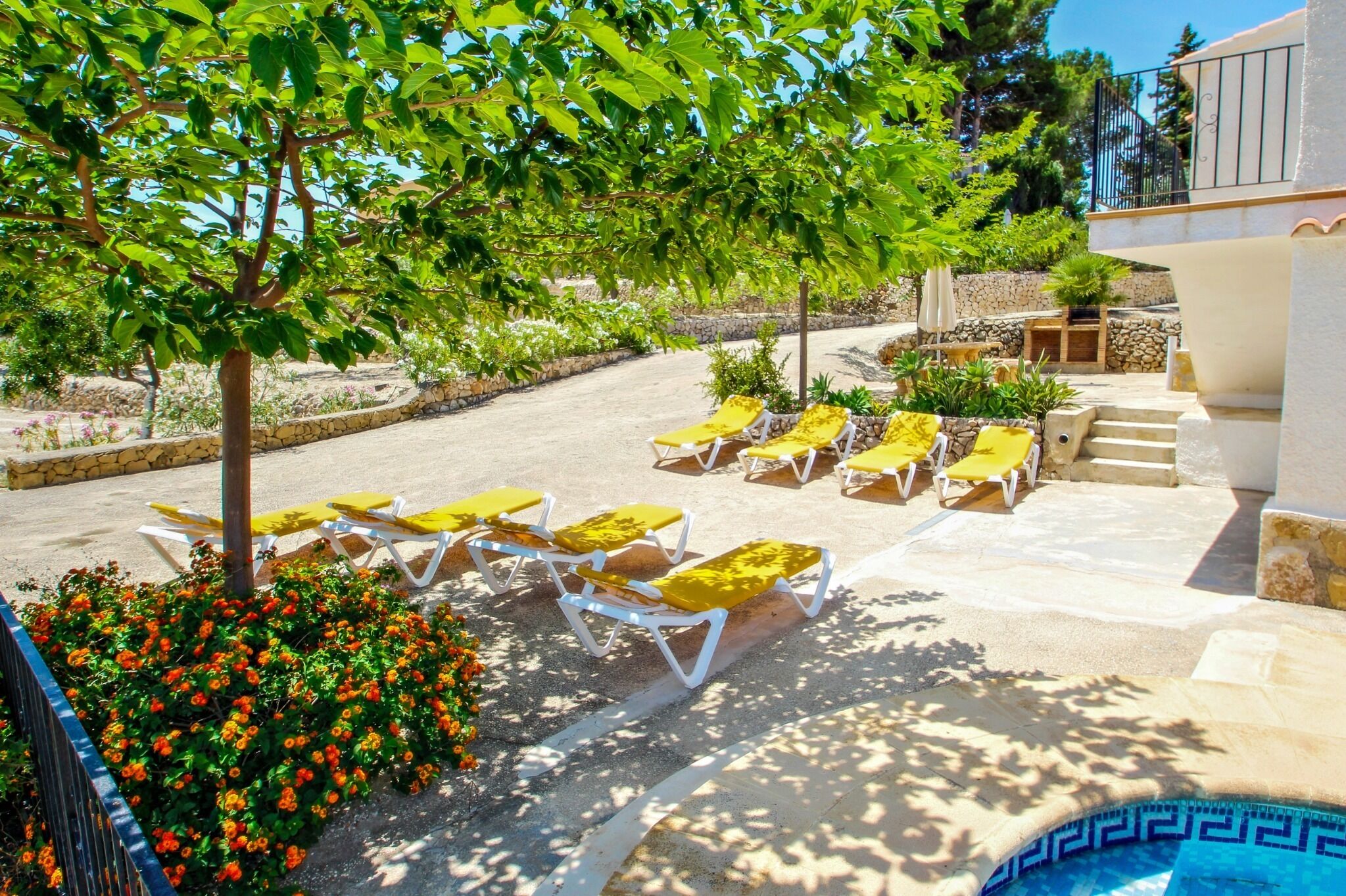 A poolside area with sun loungers and a stone wall.