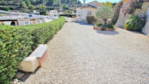 A gravel driveway leading to a house with a stone wall and a palm tree. - Alldo - modern hillside villa with pool & views (Moraira)