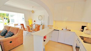 A modern kitchen with white cabinets, a built-in dishwasher, and a countertop with a coffee maker. - Alldo - modern hillside villa with pool & views (Moraira)