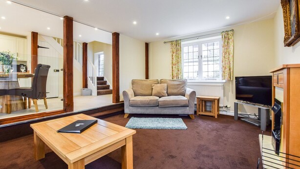 A living room with a sofa, a coffee table, a TV, and a mirror. - A sudeley castle cottage that sleeps 4 guests  in 2 bedrooms (Cheltenham)