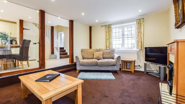 A living room with a sofa, a coffee table, a TV, and a mirror.