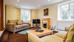 A cozy living room with a sofa, a coffee table, a TV, and a fireplace. - A sudeley castle cottage that sleeps 4 guests  in 2 bedrooms (Cheltenham)