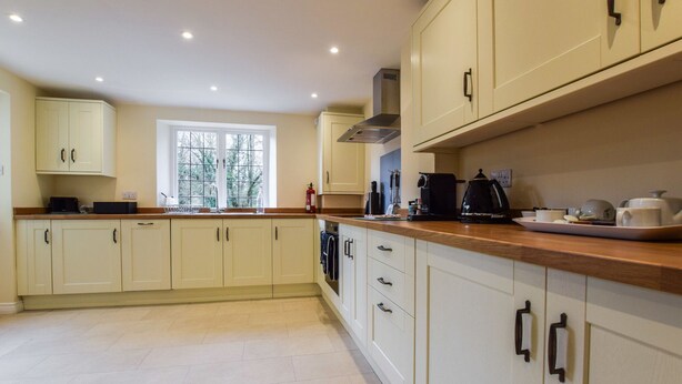 A modern kitchen with light-colored cabinets, a wooden countertop, and various appliances. - A sudeley castle cottage that sleeps 4 guests  in 2 bedrooms (Cheltenham)