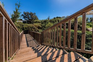 A wooden bridge with railings, surrounded by greenery and trees.