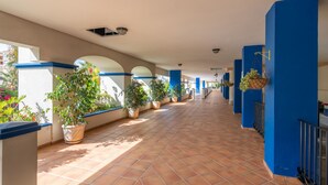 Un pasillo con piso de baldosas, paredes azules y plantas en macetas.