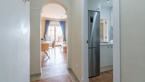 Una cocina moderna con refrigerador de acero inoxidable, armarios blancos y piso de baldosas.