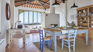 Une cuisine spacieuse avec une table en bois, des chaises bleues et une grande fenêtre.