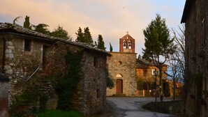 Une ruelle étroite pavée, bordée de bâtiments en pierre, avec le clocher d’une église en arrière-plan.