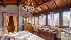 A bedroom with a wooden ceiling, a large bed with a white bedspread, a dresser, a vanity with a mirror, and a window with curtains.