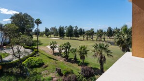 A golf course with a clear sky, palm trees, and a building with a white facade. - La Quinta de Isla Canela II - Isla Canela Golf GQHII10P10 (Isla Canela)