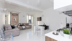 Un salon moderne avec un canapé, une table à manger et des chaises. Il y a également un coin cuisine équipé d’une cuisinière et d’un évier.