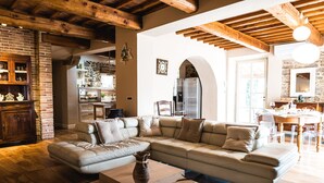 A spacious living room with a large sectional sofa, wooden flooring, and exposed wooden beams.