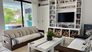 A living room with a sofa, coffee table, and a bookshelf with books and a TV.