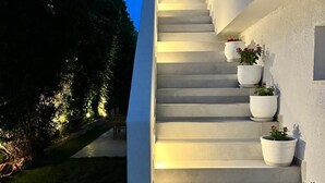 A modern staircase with white walls and potted plants.
