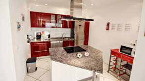 Una cocina moderna con gabinetes rojos, electrodomésticos de acero inoxidable y encimera de granito.
