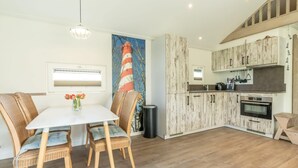 Une cuisine moderne avec des meubles en bois, un coin repas avec des chaises en osier et un tableau accroché au mur.