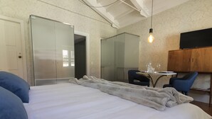 A bedroom with a bed, a table with glasses, a chair, and a wardrobe. - The Brewmaster's House 3 | Superior Studio (Porto)