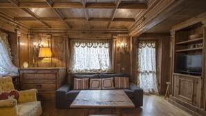Une pièce aux murs lambrés, avec un canapé, une table basse et un téléviseur posé sur un meuble en bois.