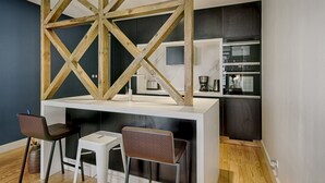 Eine moderne Küche mit weißer Arbeitsplatte, zwei Barhocker und einer Holzbalkendecke.