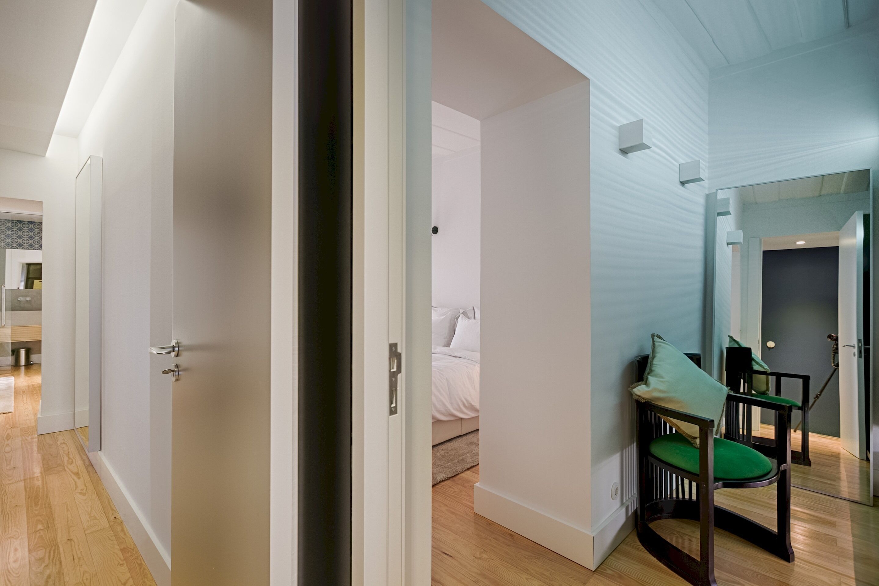 Une chambre d’hôtel moderne avec un plancher en bois, un lit avec une literie blanche, une chaise verte et une petite table.