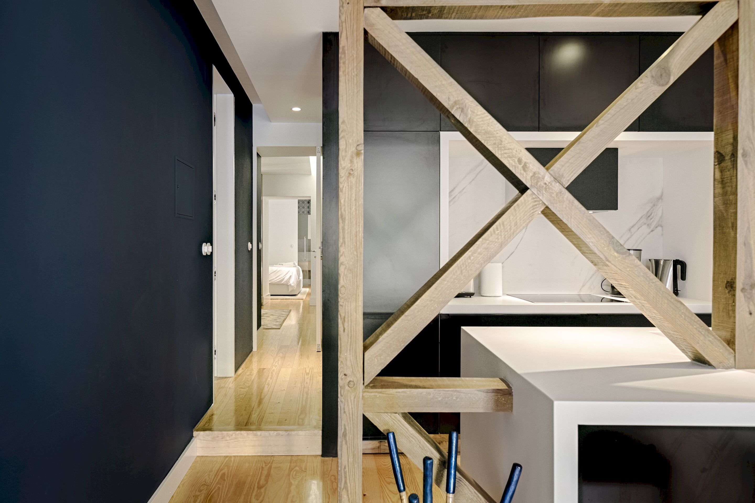 A modern kitchen with a wooden beam structure, a white countertop, and a dark wall.